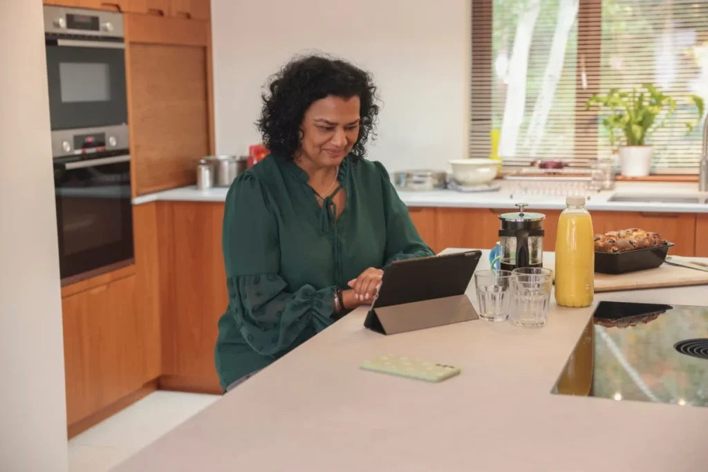 Woman sitting at kitchen bench at home making an NDIS referral