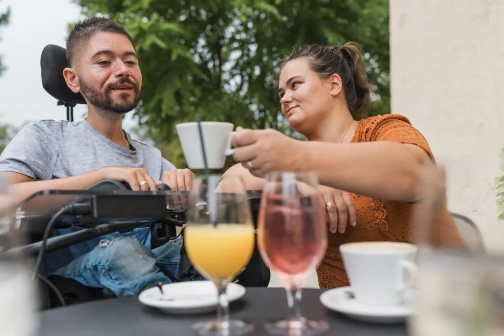 Support worker with disabled man in wheelchair at cafe